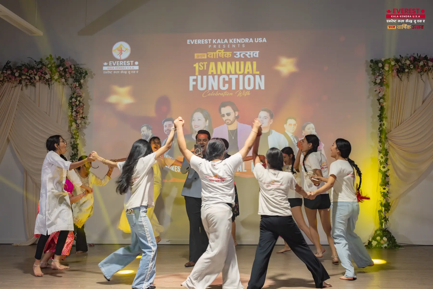 A group of EKK dancers in matching white and grey outfits performing an ensemble routine