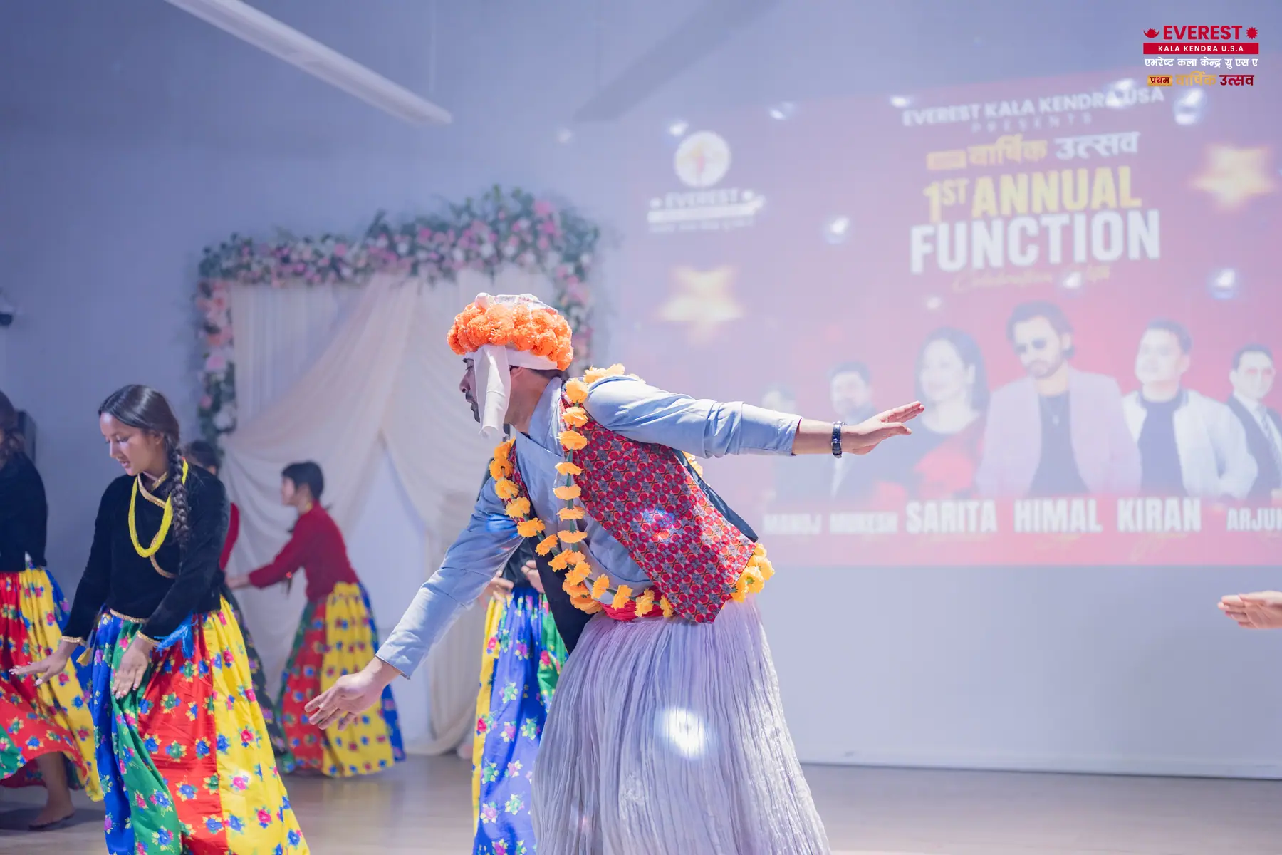 EKK performers in colorful traditional Nepali costumes dancing together on stage