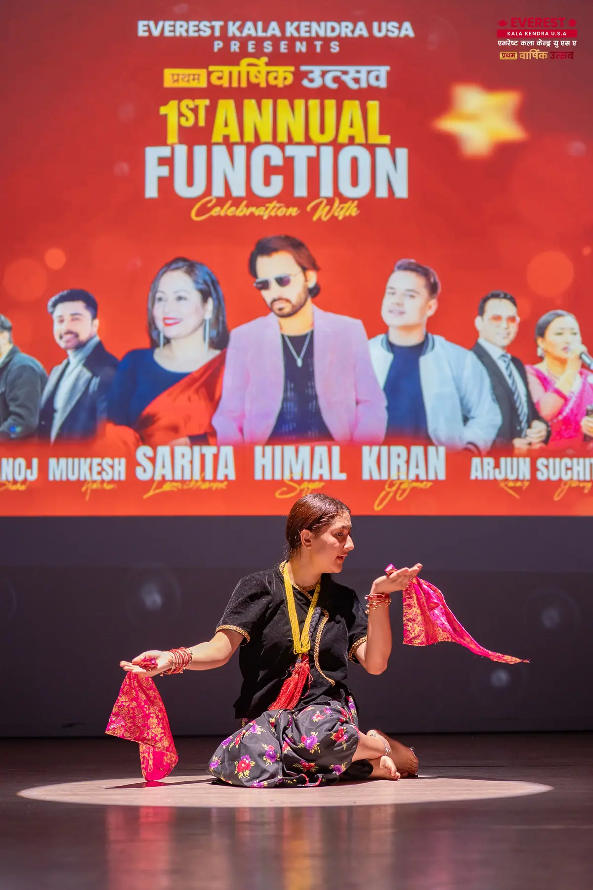An EKK host speaking at the podium in front of the annual function performer lineup banner