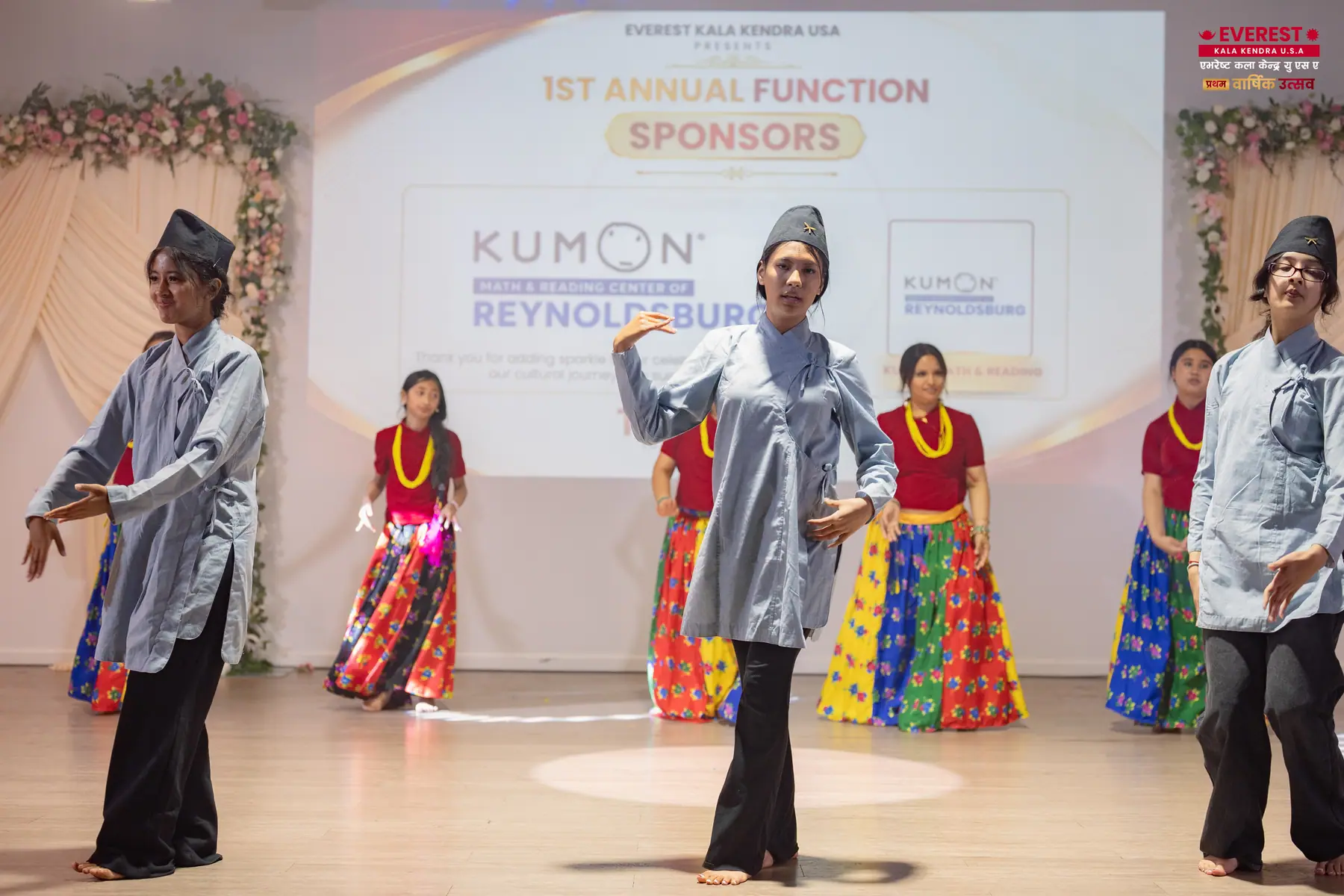 A row of EKK dancers in brightly striped traditional skirts performing in unison