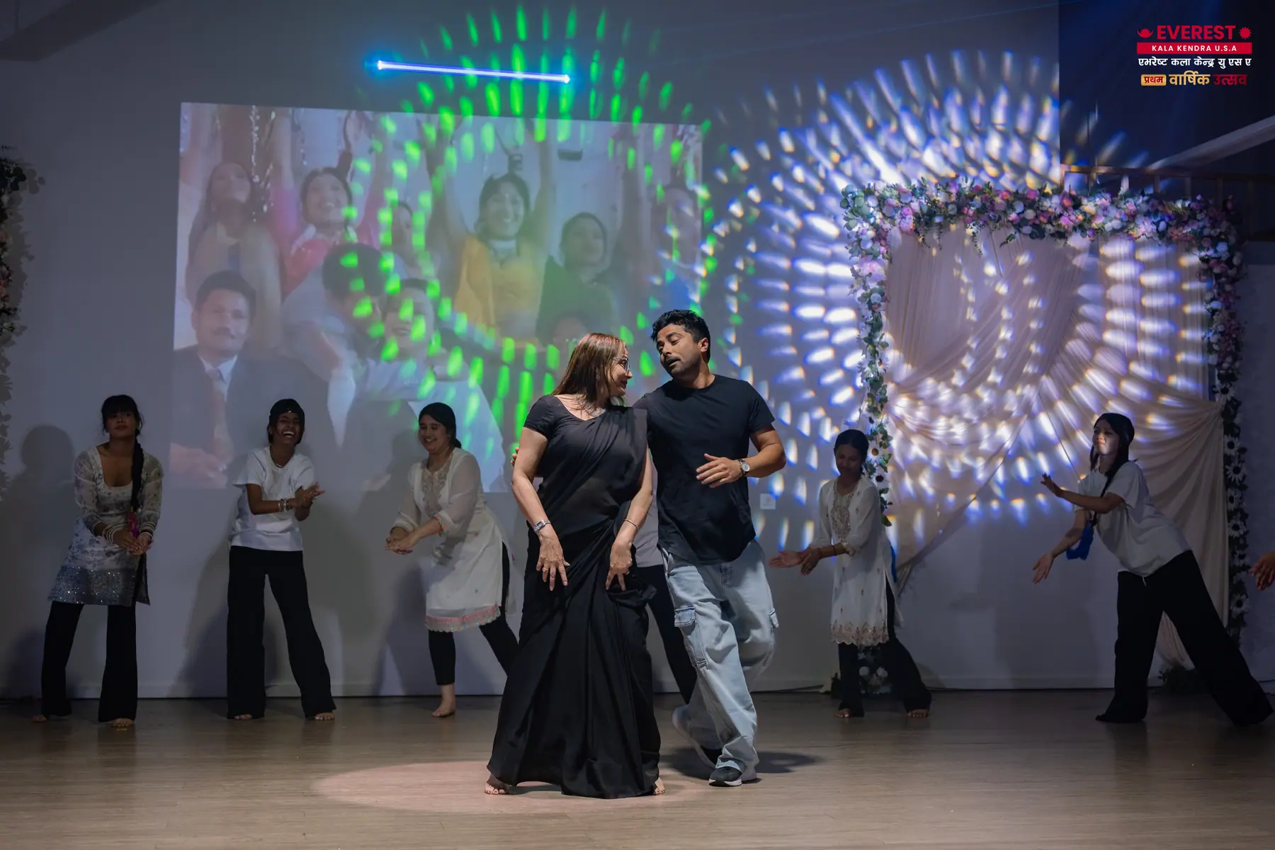 A pair of EKK performers dancing in front of an illuminated circular stage backdrop