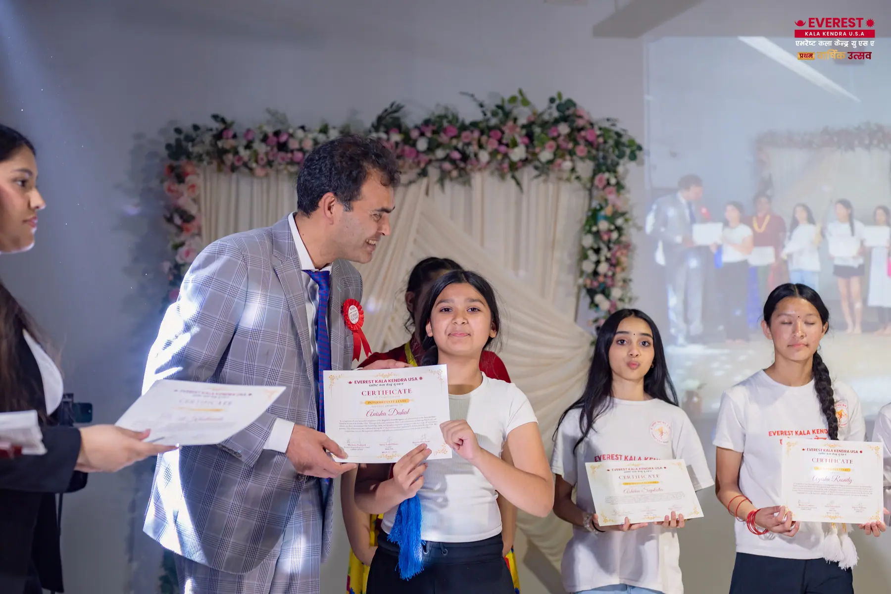 A group of EKK students on stage holding their achievement certificates and smiling
