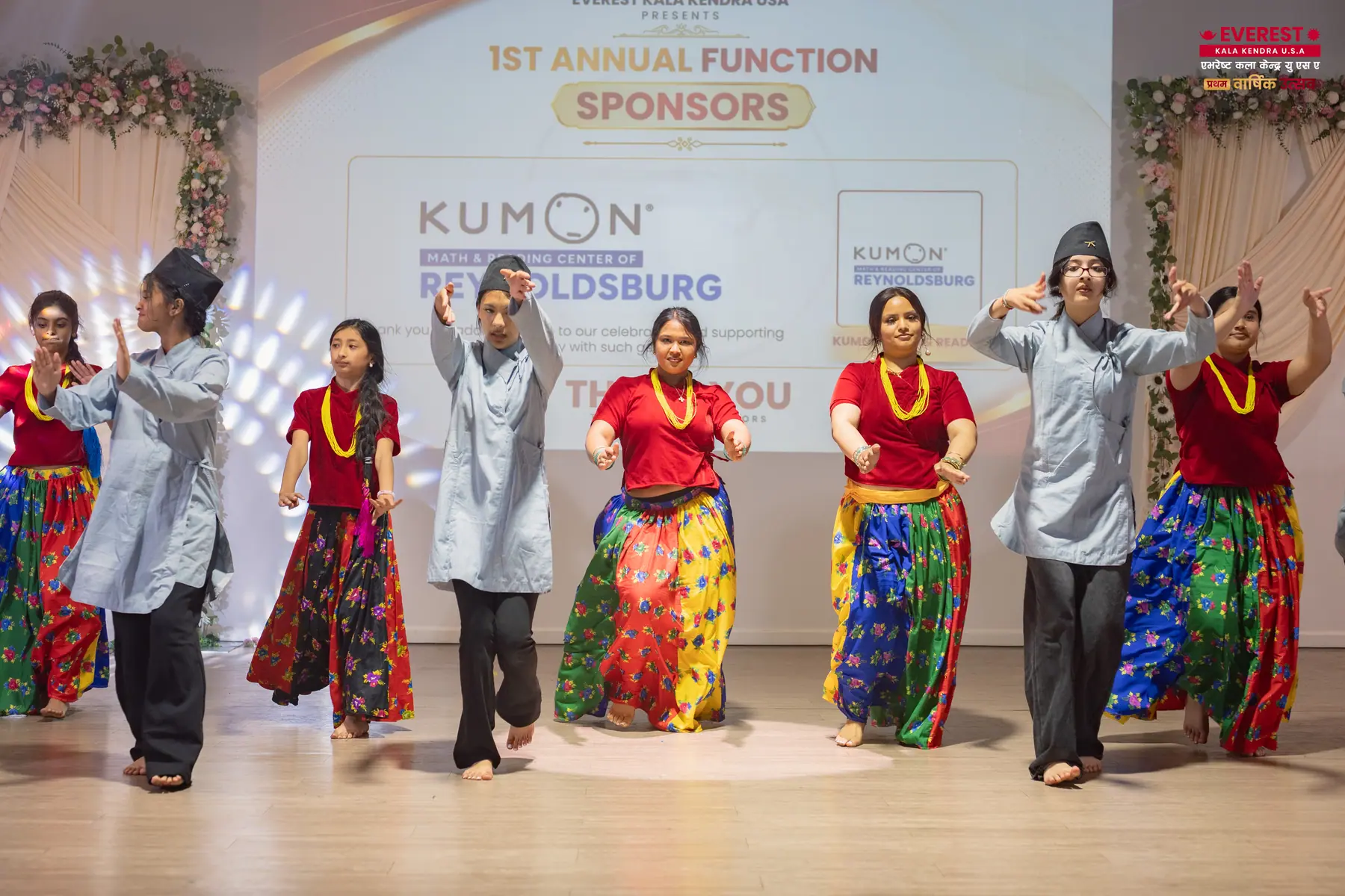 EKK dancers in traditional dress performing synchronized choreography across the stage