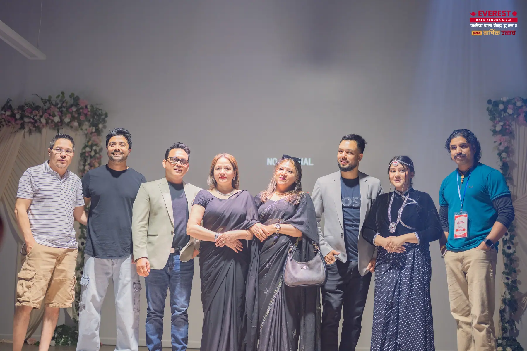A line of EKK volunteers and staff posing together on stage after the event