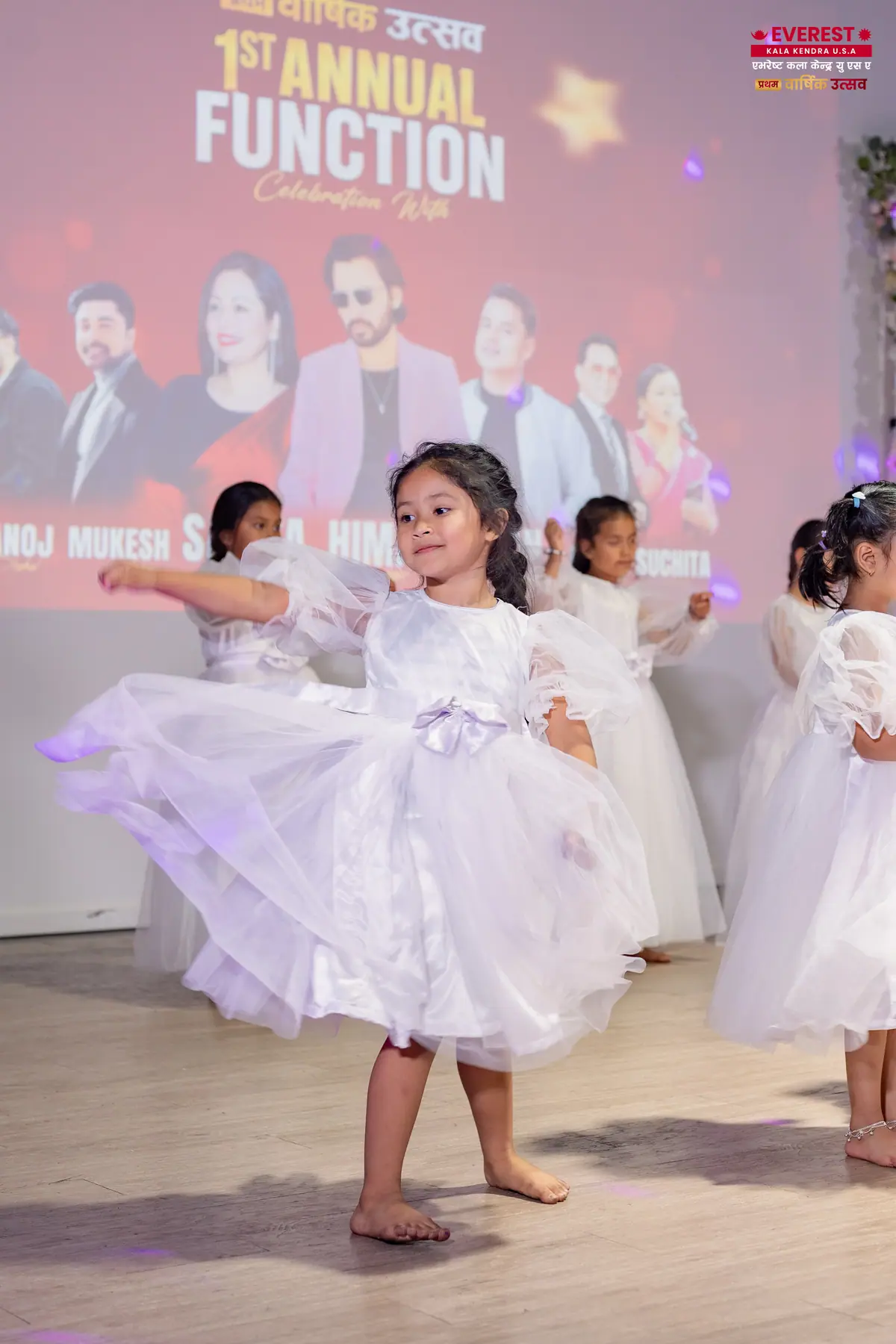 A young EKK student in a white dress captured mid-turn during a stage performance