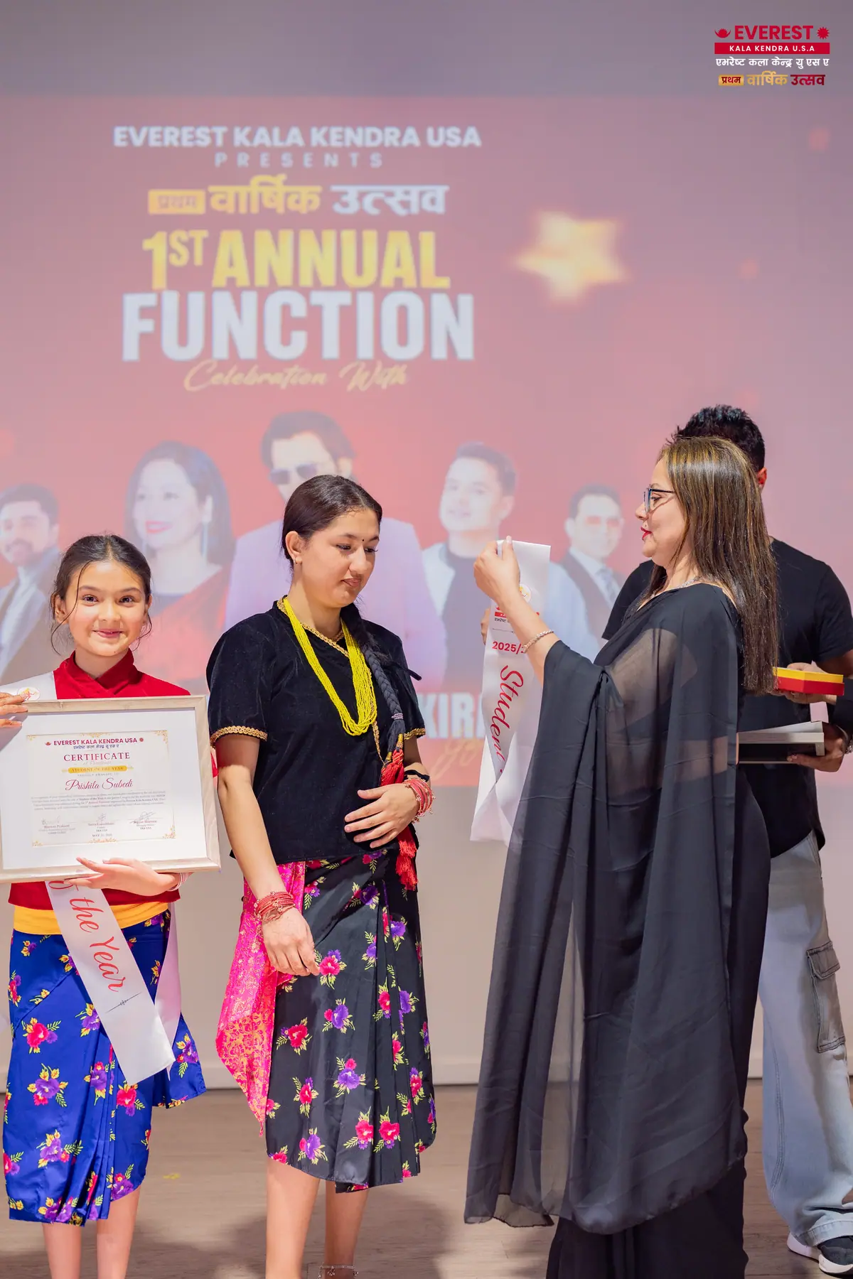 A young EKK student receives an achievement certificate from a staff member